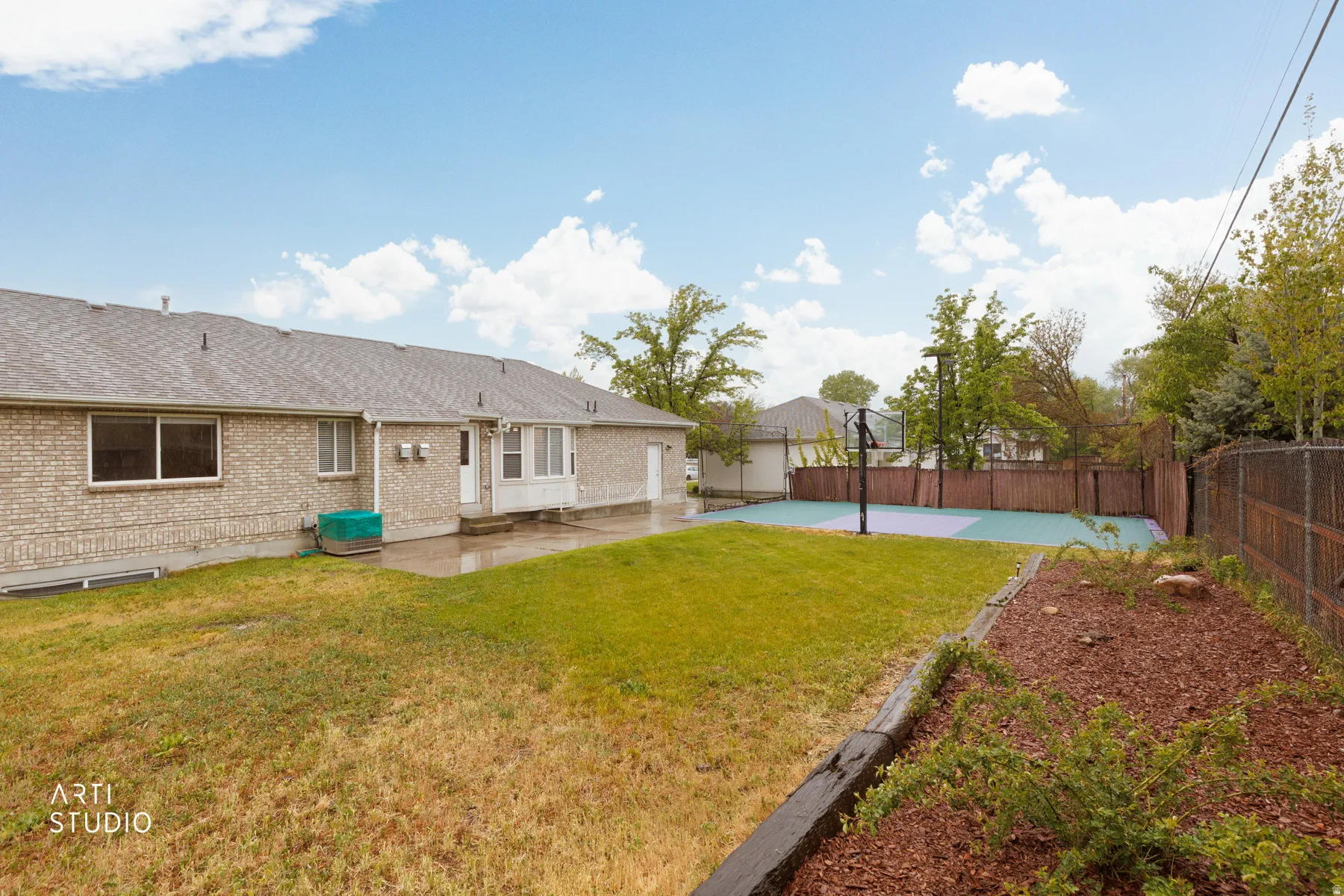 Rear view of property with roof with shingles, a fenced backyard, brick siding, and a patio