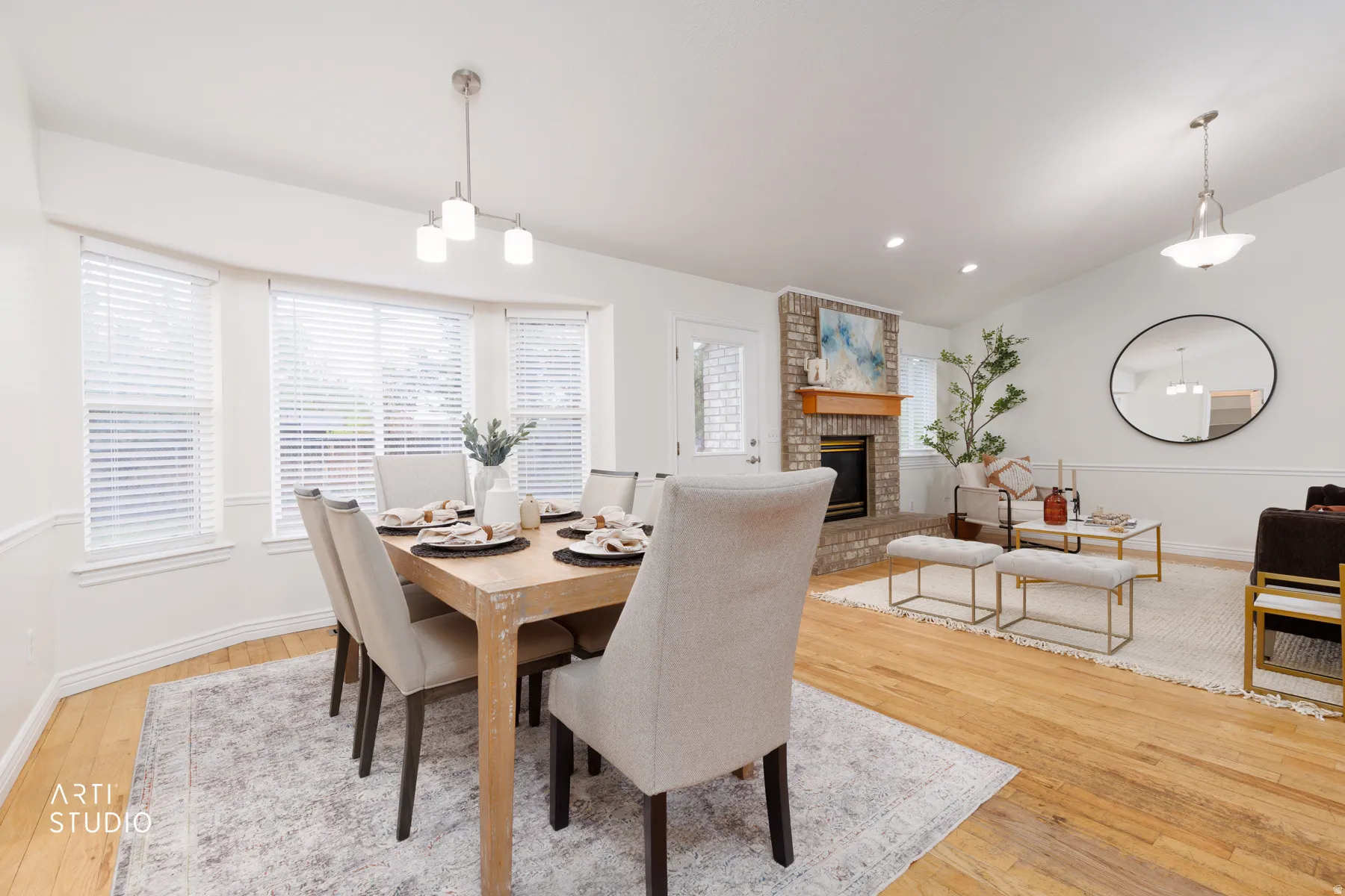 Dining room with vaulted ceiling, light wood finished floors, a brick fireplace, and hanging lights