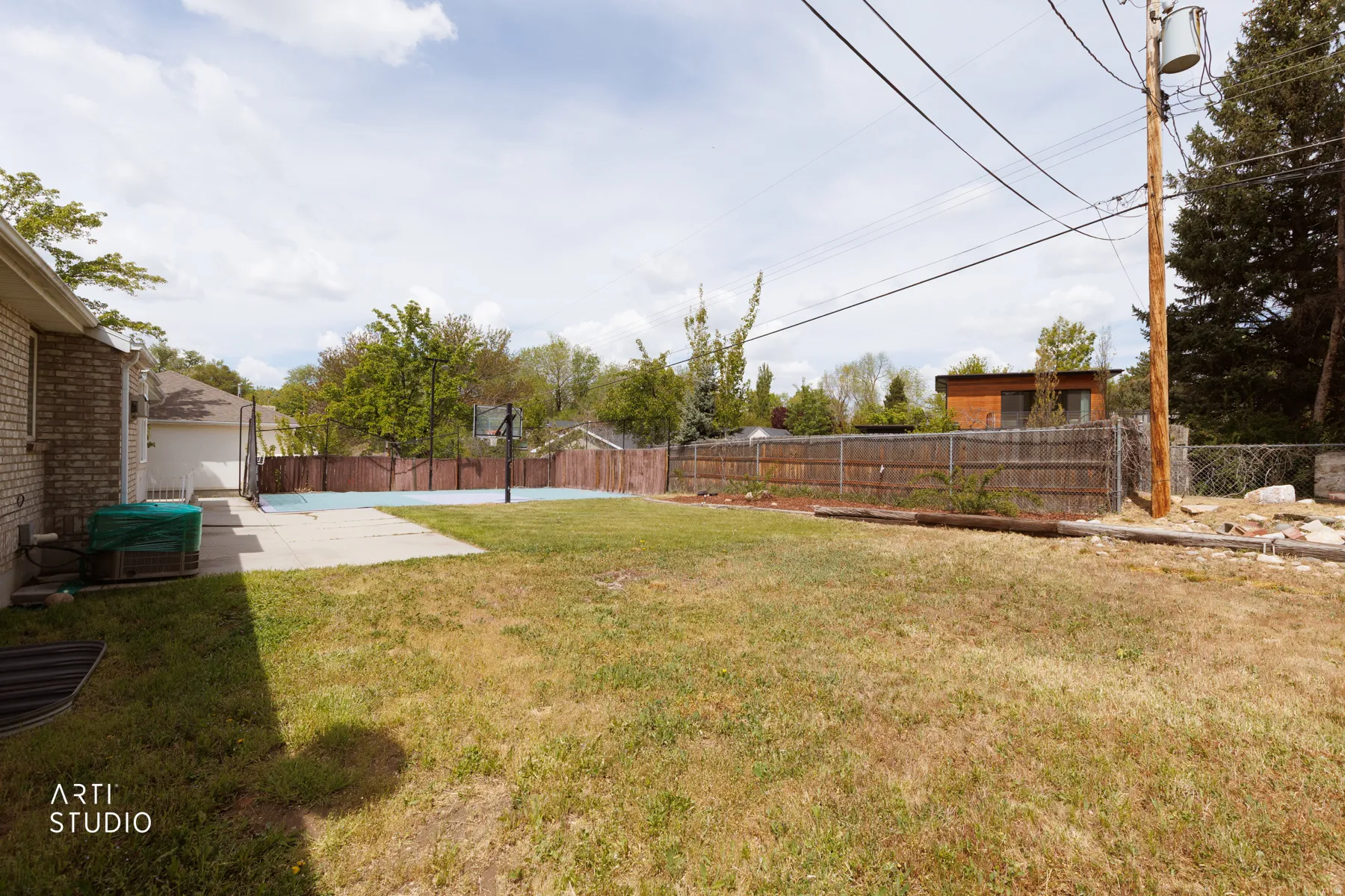 Fenced backyard featuring a patio and basketball court