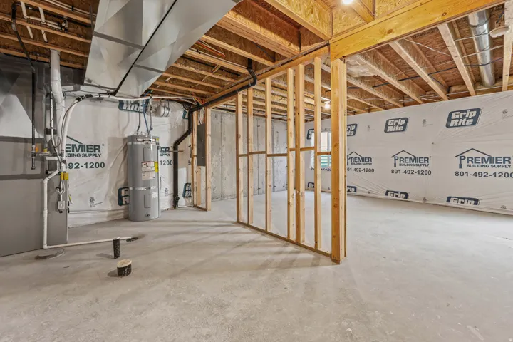 Unfinished below grade area with heating unit, water heater, and electric panel