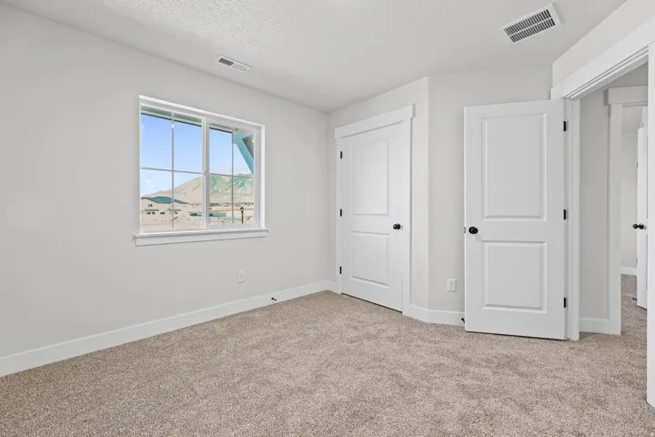 Unfurnished bedroom with light carpet and a textured ceiling