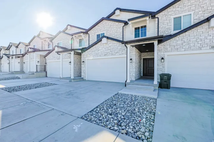 View of front facade with stone siding, driveway, a residential view, and an attached garage