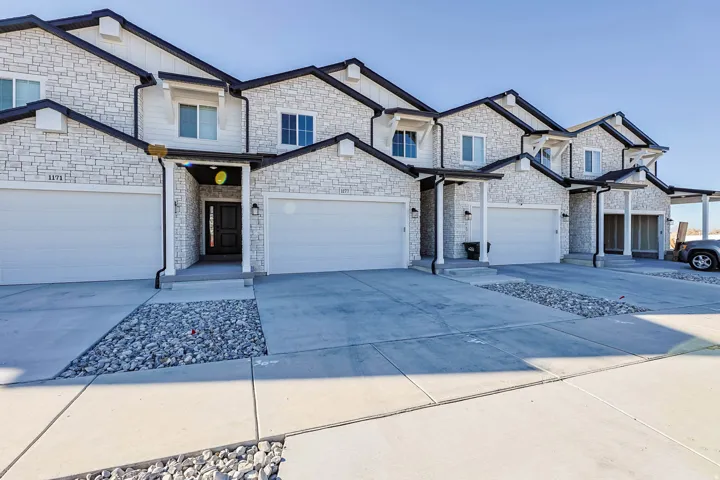 View of front of property with concrete driveway, stone siding, and board and batten siding