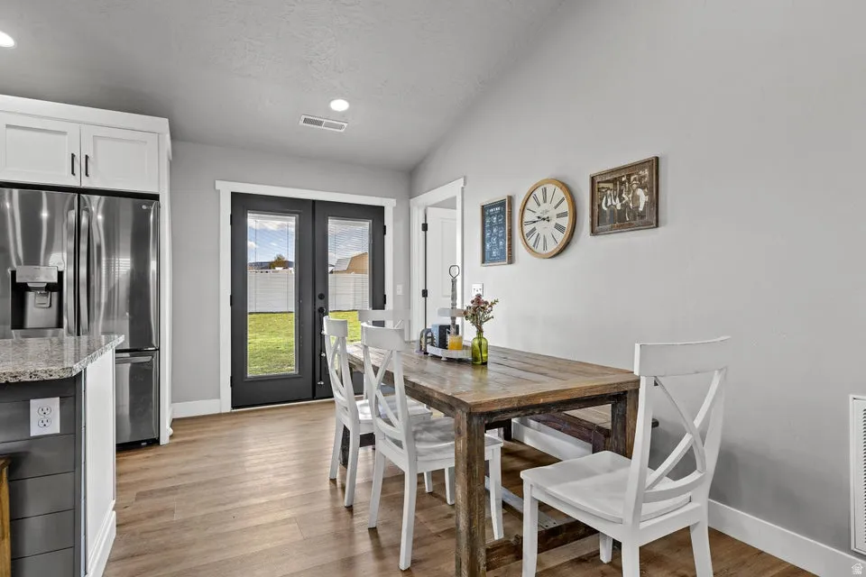 Dining room with french doors, light wood-style flooring, vaulted ceiling, and recessed lighting