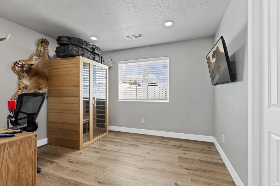 Office space featuring a sauna, light wood finished floors, a textured ceiling, and recessed lighting