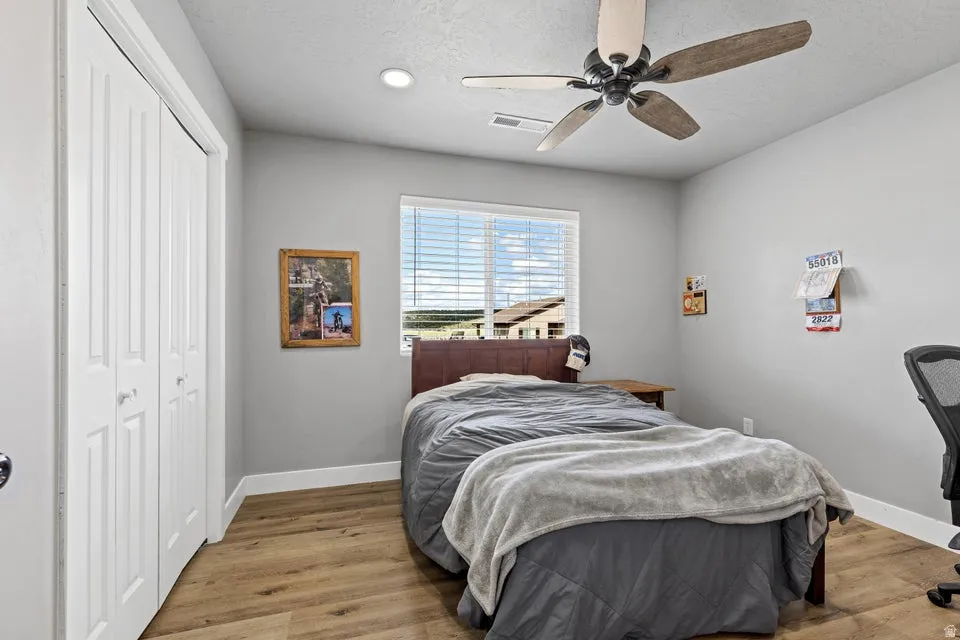 Bedroom with wood finished floors, a closet, and a ceiling fan