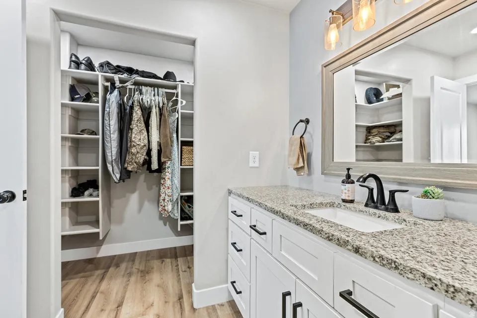 Bathroom featuring a spacious closet, vanity, and light wood finished floors
