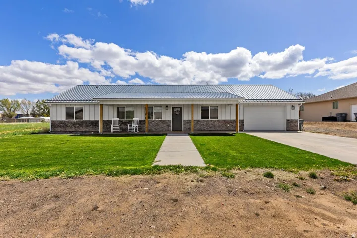 View of front of home featuring board and batten siding, covered porch, driveway, an attached garage, and a front yard