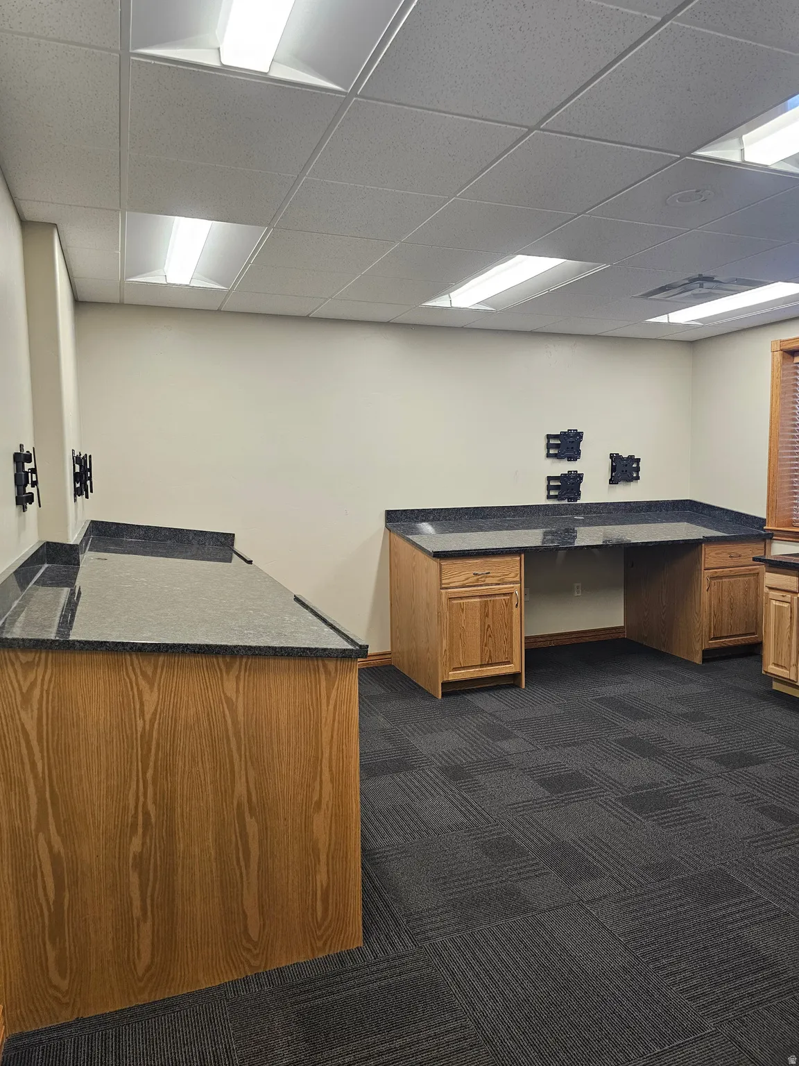 Commercial space featuring durable carpet tile flooring and multiple workstations with wood-finish cabinetry