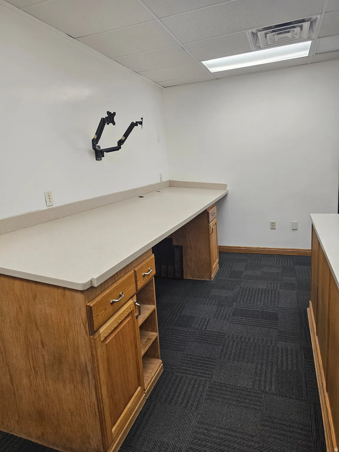 Spacious room featuring a long built-in countertop with light-toned surface and wood-finish cabinetry