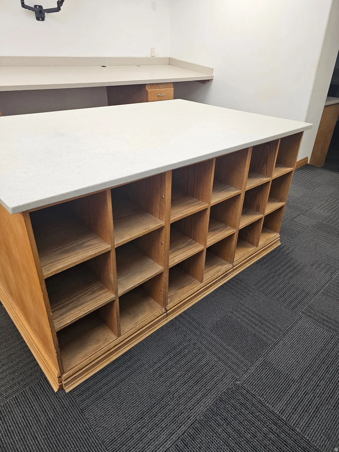 Built-in oak shelving unit with a light-toned countertop, complemented by a perimeter built-in counter with an integrated sink cutout