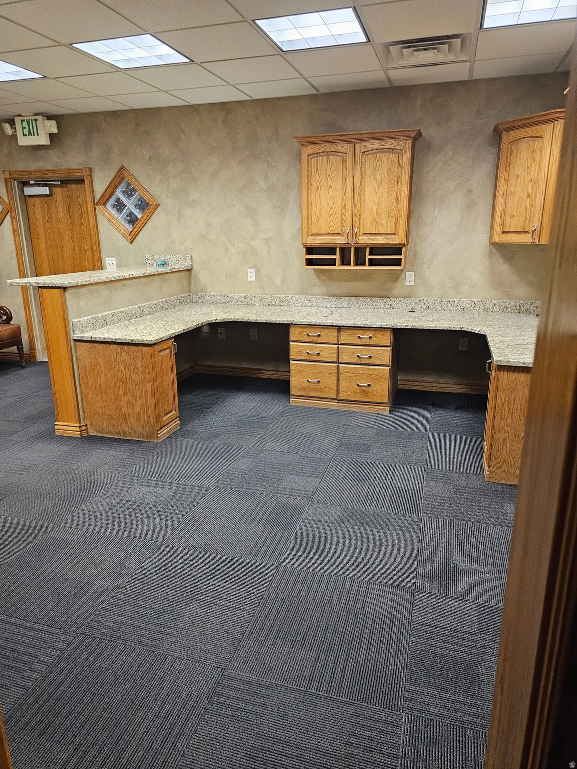 Expansive counter space featuring light-toned countertops, wood-finish cabinetry, and square ceiling tiles with recessed lighting