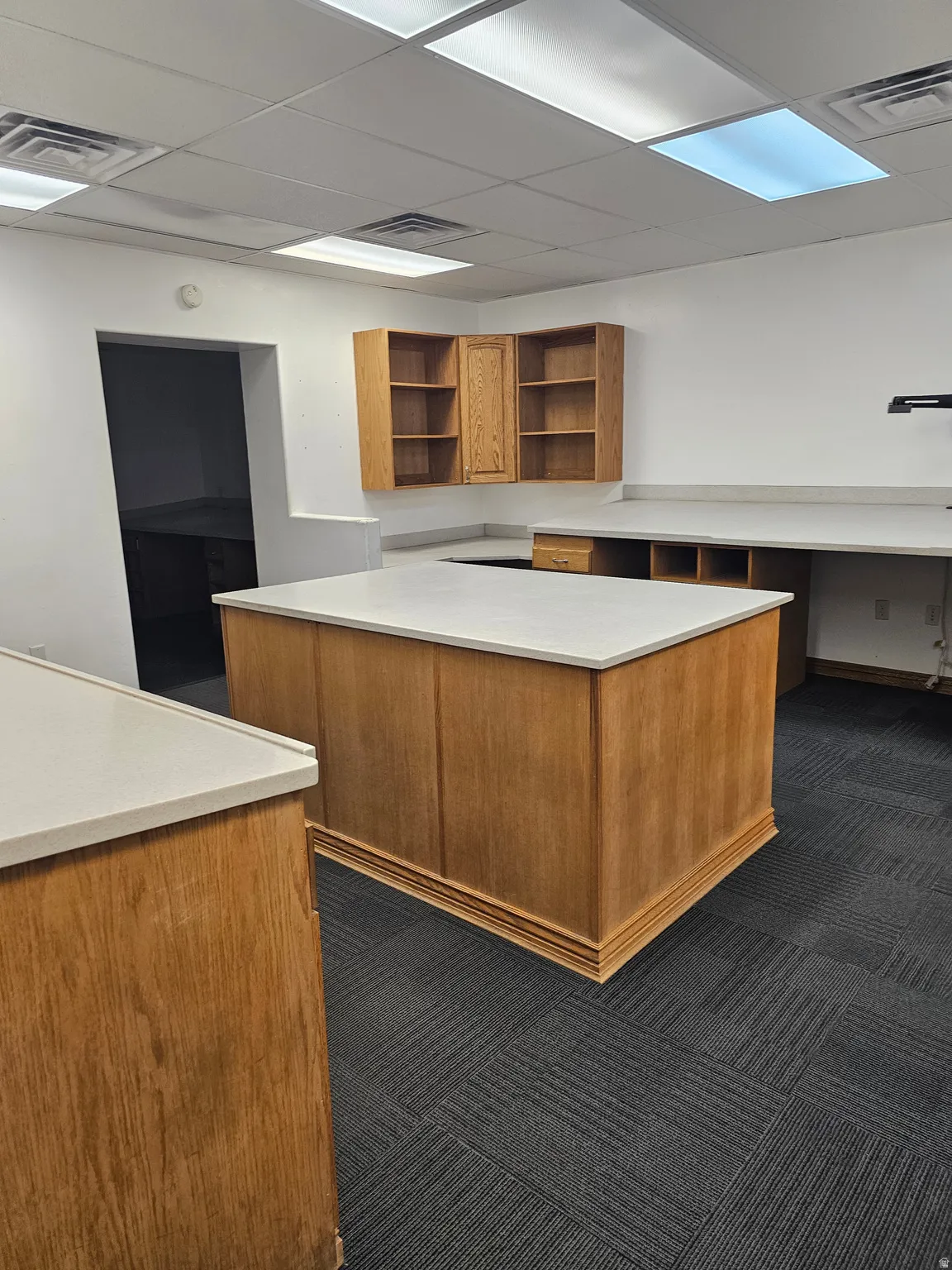 Spacious work area featuring a central island with a light-toned countertop, complementing extensive perimeter countertops