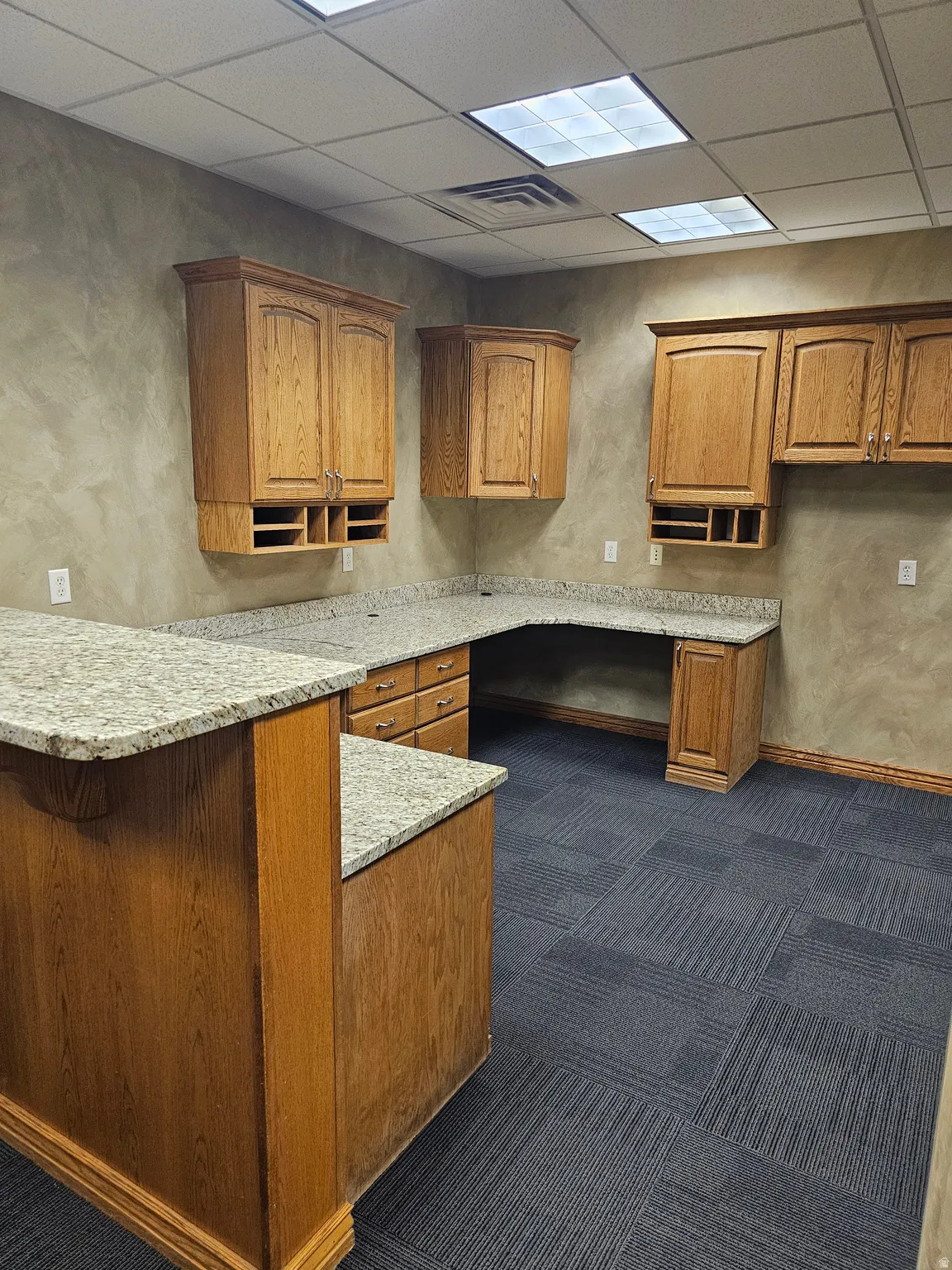 Built-in cabinetry with a wood-finish, granite-style countertops, and integrated desk space