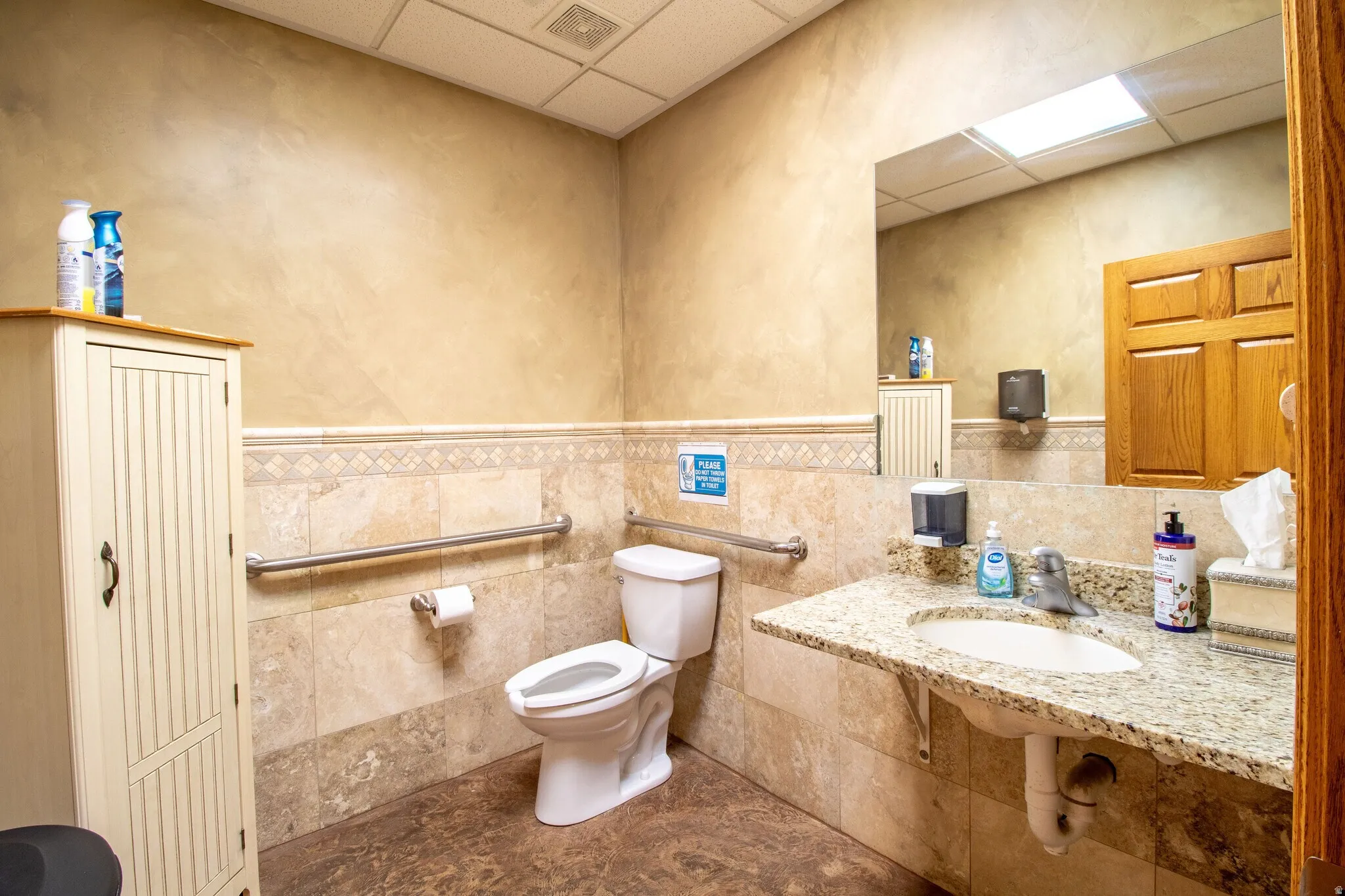 Half bathroom with a paneled ceiling, tile walls, a wainscoted wall, and a textured wall