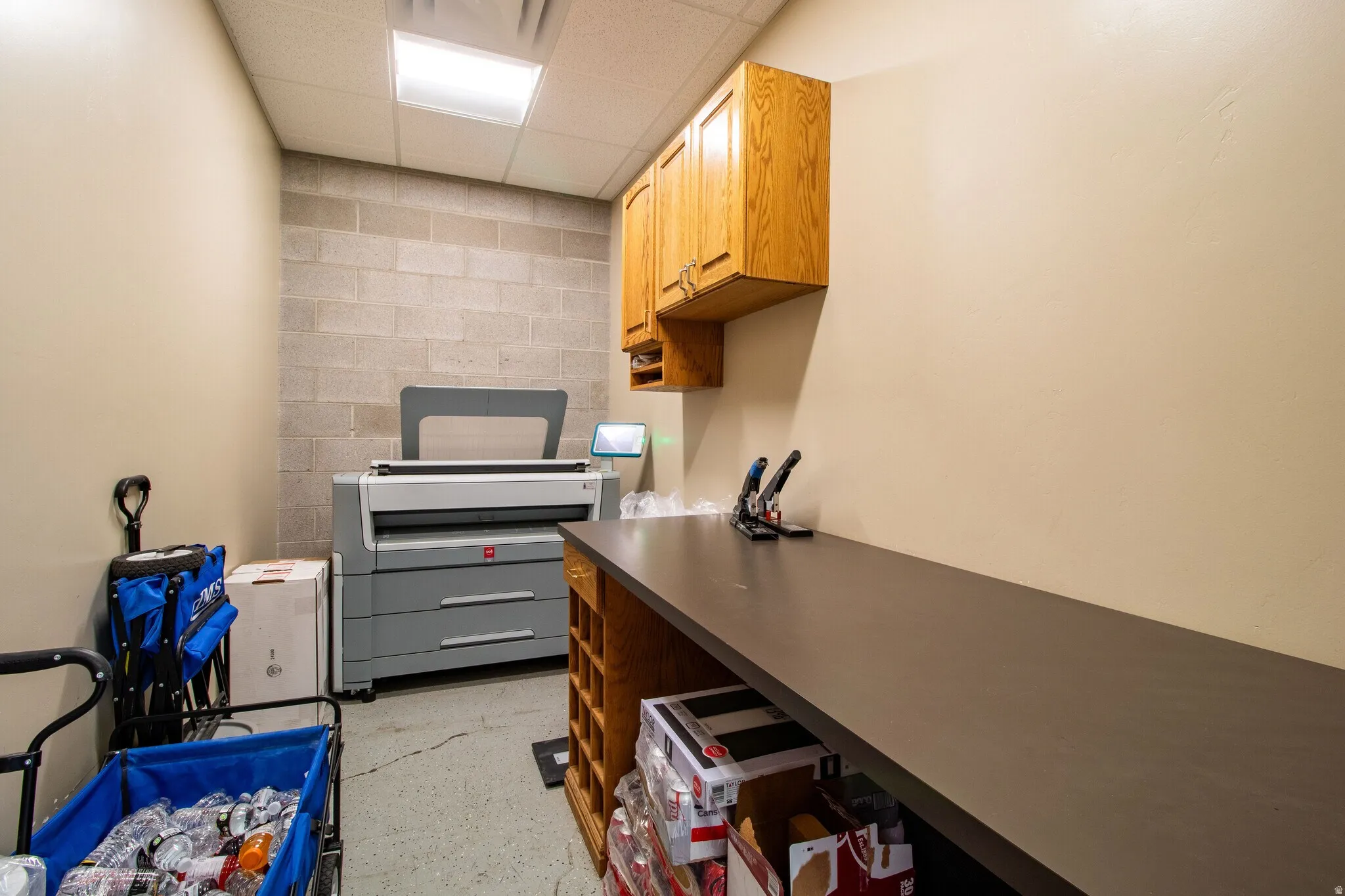 Kitchen featuring a drop ceiling, concrete block wall, and dark countertops