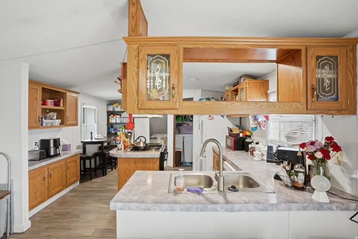 Kitchen with wood finish cabinets, a peninsula, light countertops, open shelves, and dark wood-style floors