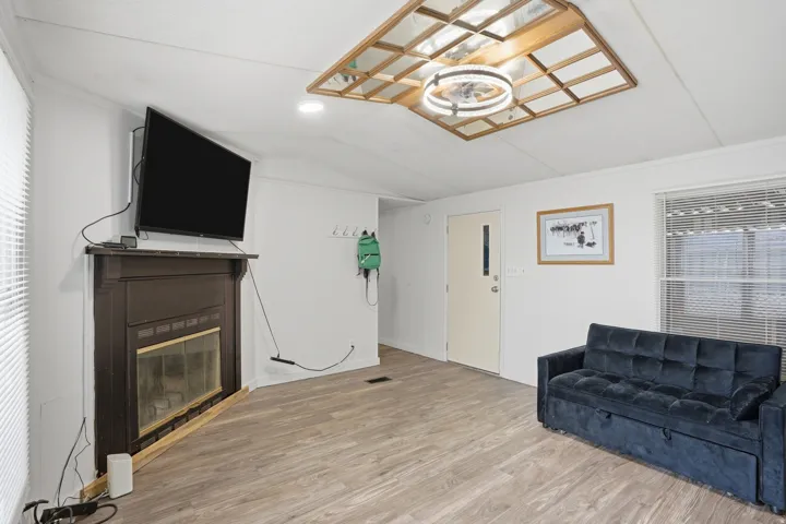 Unfurnished living room with light wood-type flooring, a glass covered fireplace, lofted ceiling, and plenty of natural light