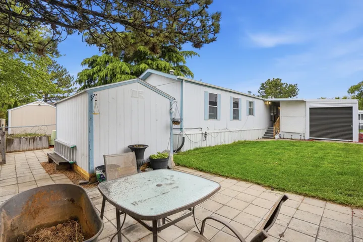 View of front of house with a patio and a shed