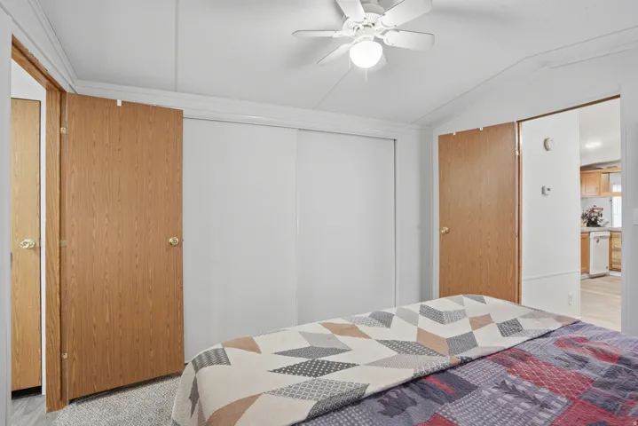 Bedroom with vaulted ceiling, a closet, ceiling fan, and light carpet