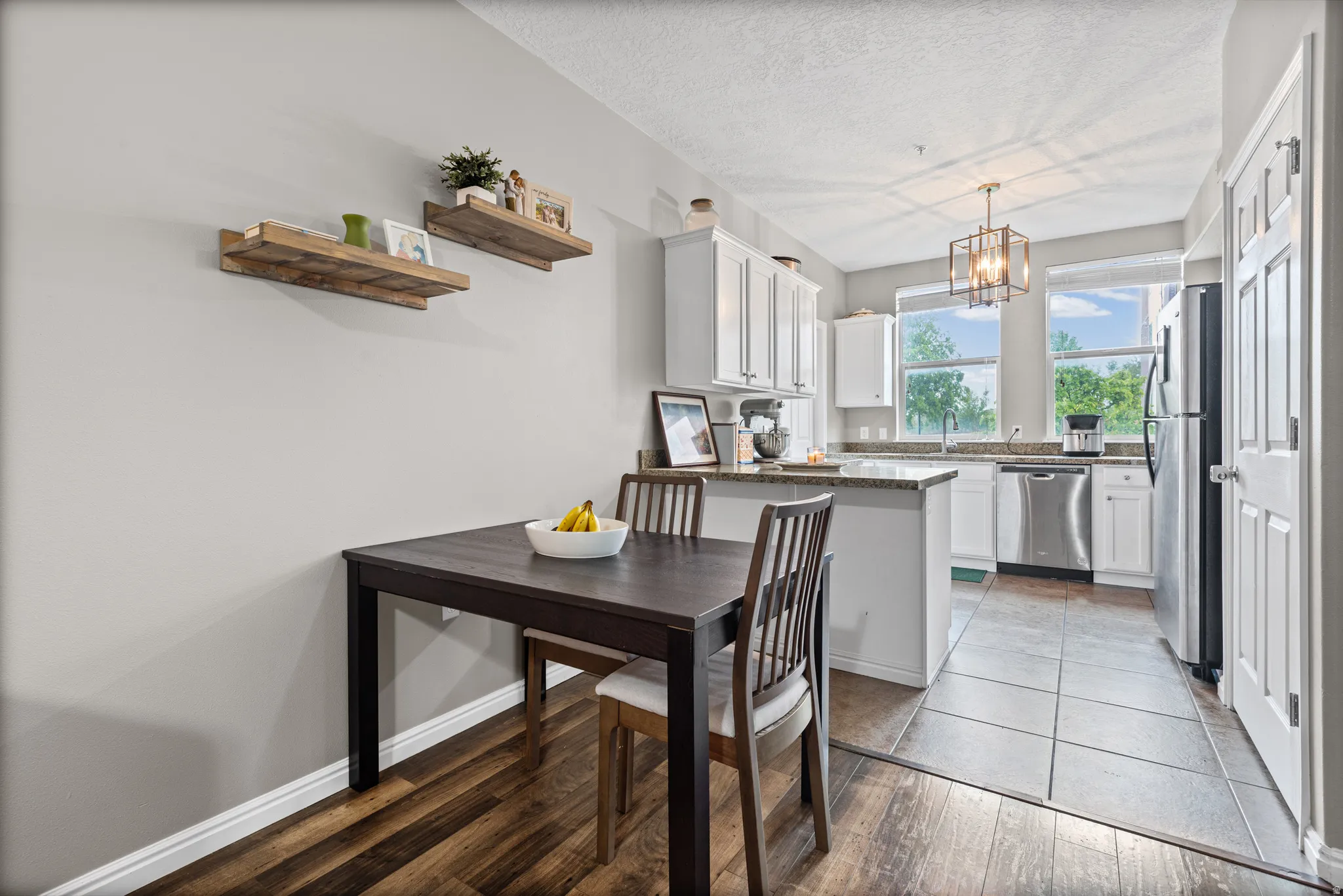 Kitchen featuring stainless steel appliances, dark stone countertops, light wood-style floors, white cabinetry, and a textured ceiling