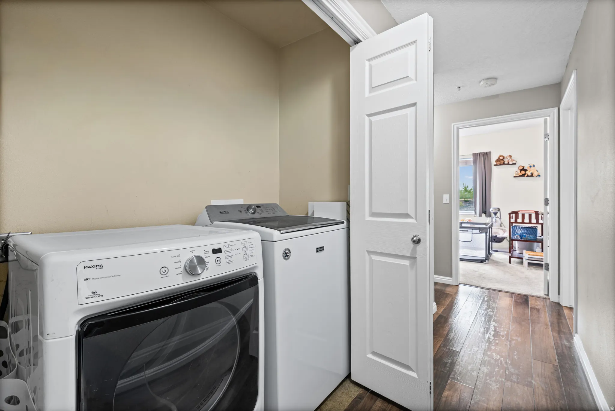 Laundry area with dark wood-style floors and washing machine and clothes dryer