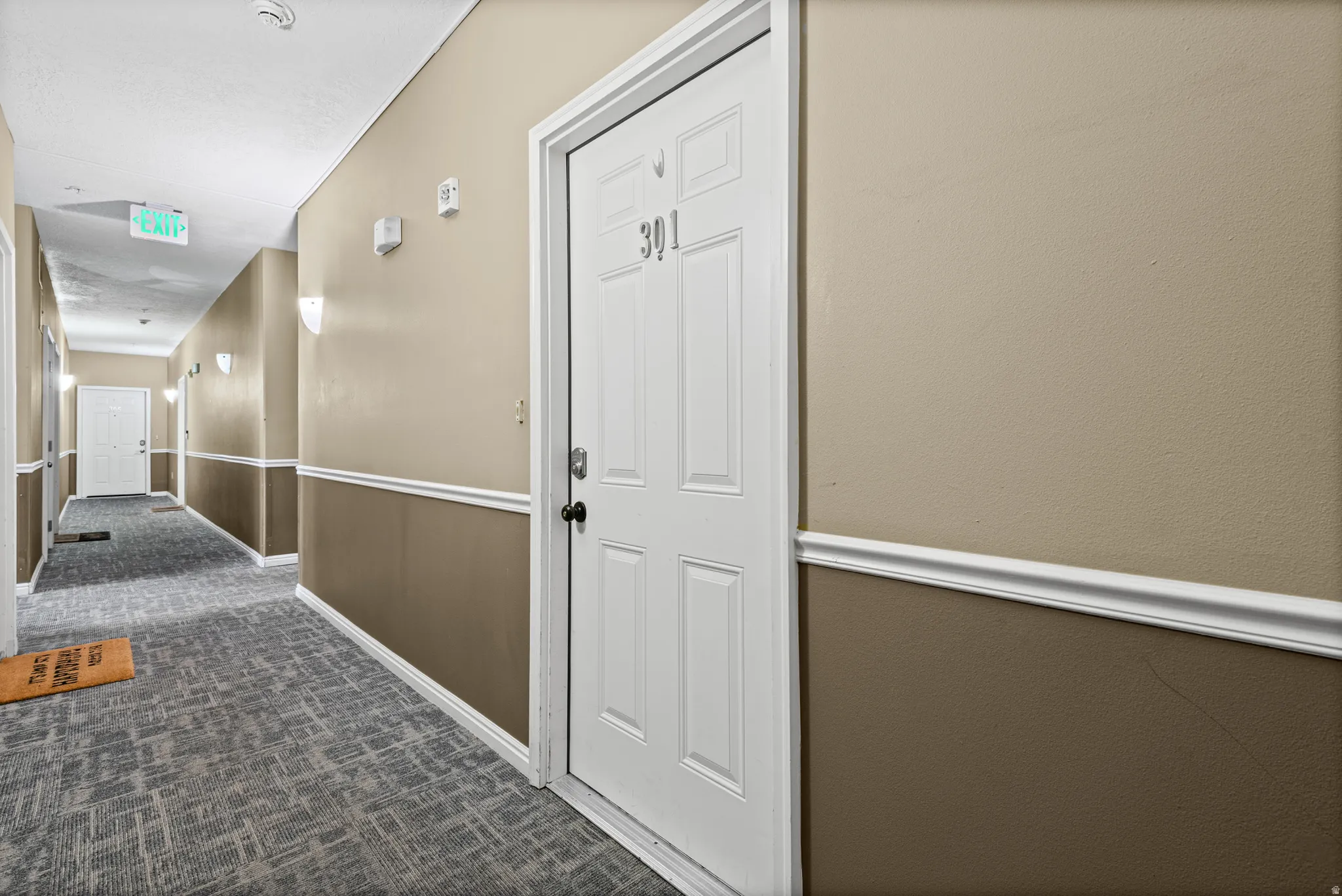 Hallway featuring dark colored carpet and baseboards