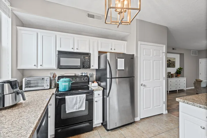 Kitchen featuring black appliances, white cabinetry, light countertops, and a textured ceiling