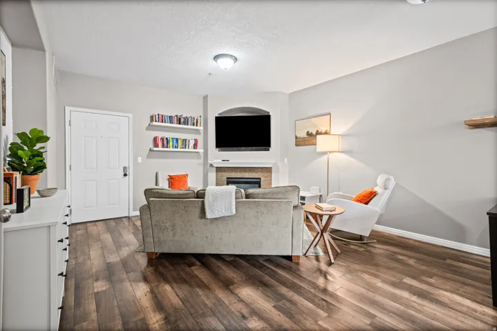 Living room featuring a textured ceiling, dark wood finished floors, a glass covered fireplace, and built in shelves