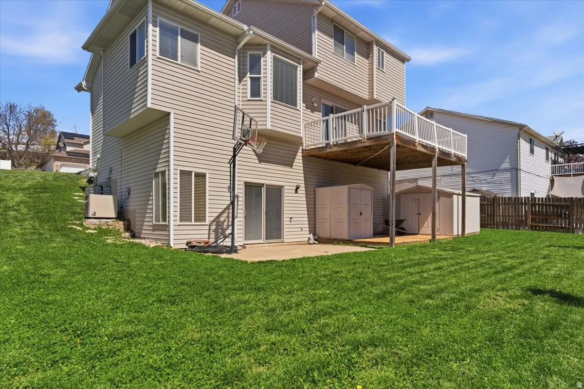 Rear view of house with a shed, a yard, a patio area, and a wooden deck