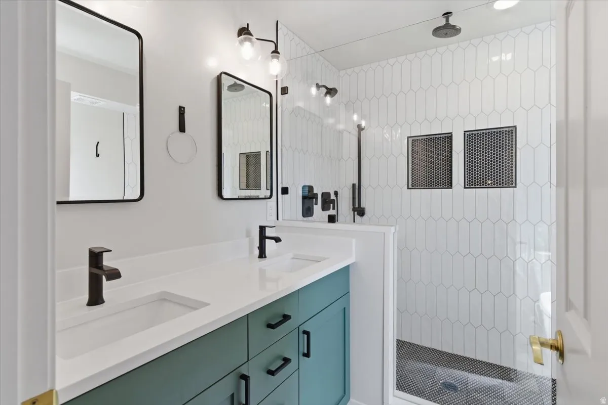 Full bathroom featuring double vanity and a tile shower