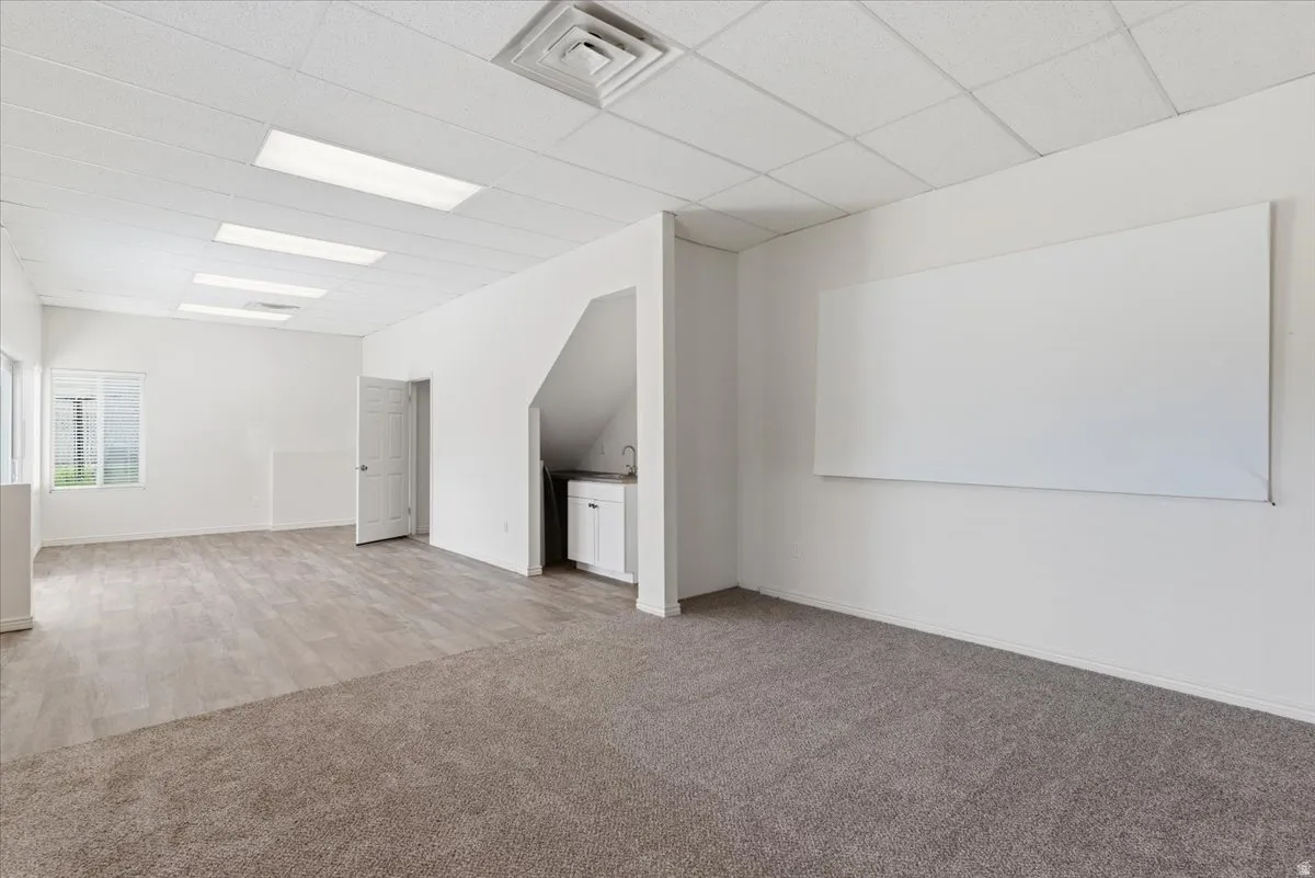 Additional living space featuring light colored carpet and baseboards