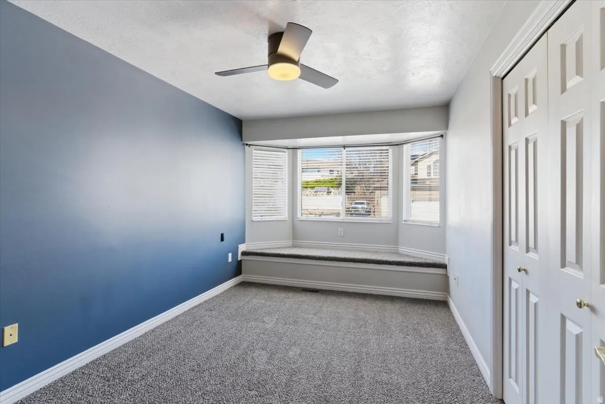 Carpeted spare room with a ceiling fan and a textured ceiling