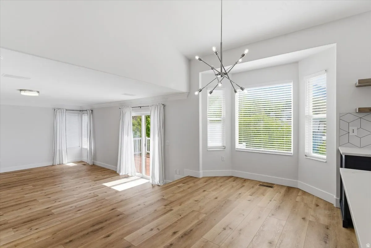 Unfurnished dining area featuring light wood-type flooring, suspended lighting, and healthy amount of natural light