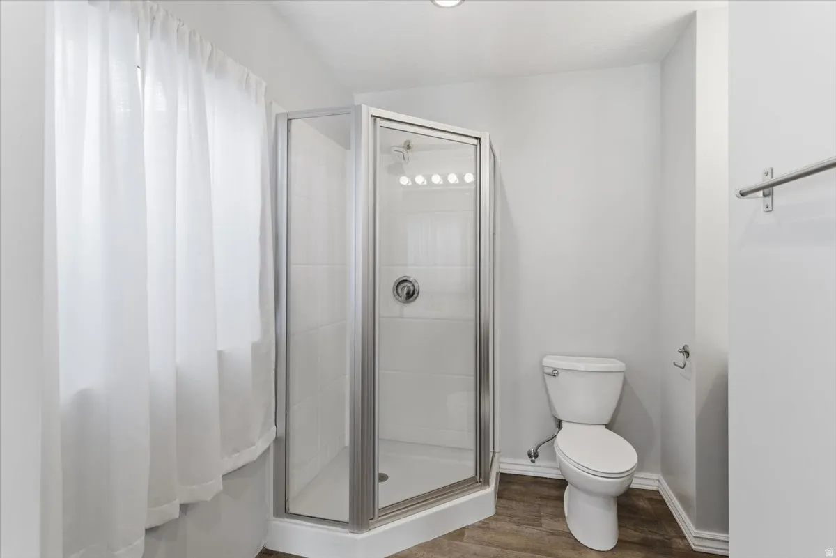 Bathroom featuring a shower stall and dark wood finished floors