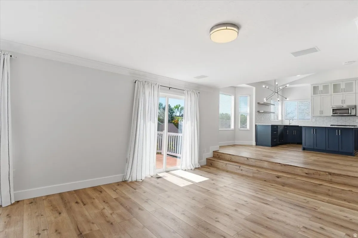 Unfurnished living room with light wood-type flooring and hanging lights