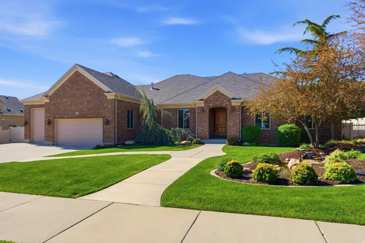 Ranch-style house featuring a shingled roof, brick siding, an attached garage, and concrete driveway