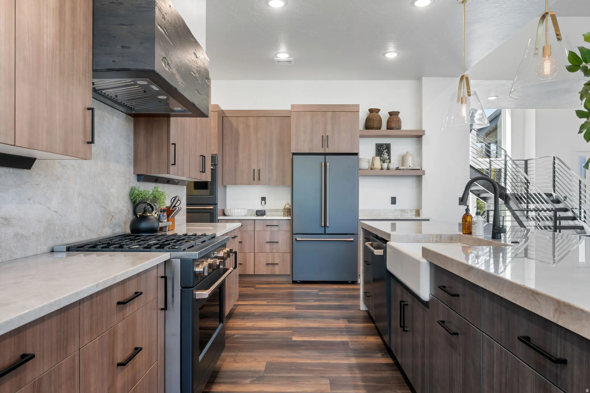 Dual tone kitchen featuring light stone countertops, high quality appliances, dual tone cabinetry, pendant lighting, and open shelves