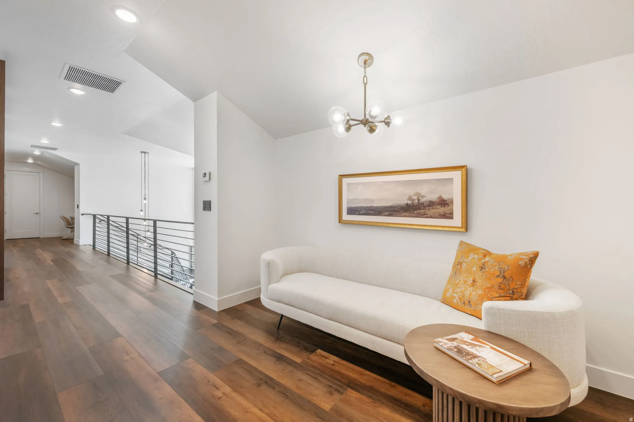 Sitting room featuring dark wood-style flooring, suspended lighting, an upstairs landing, and lofted ceiling