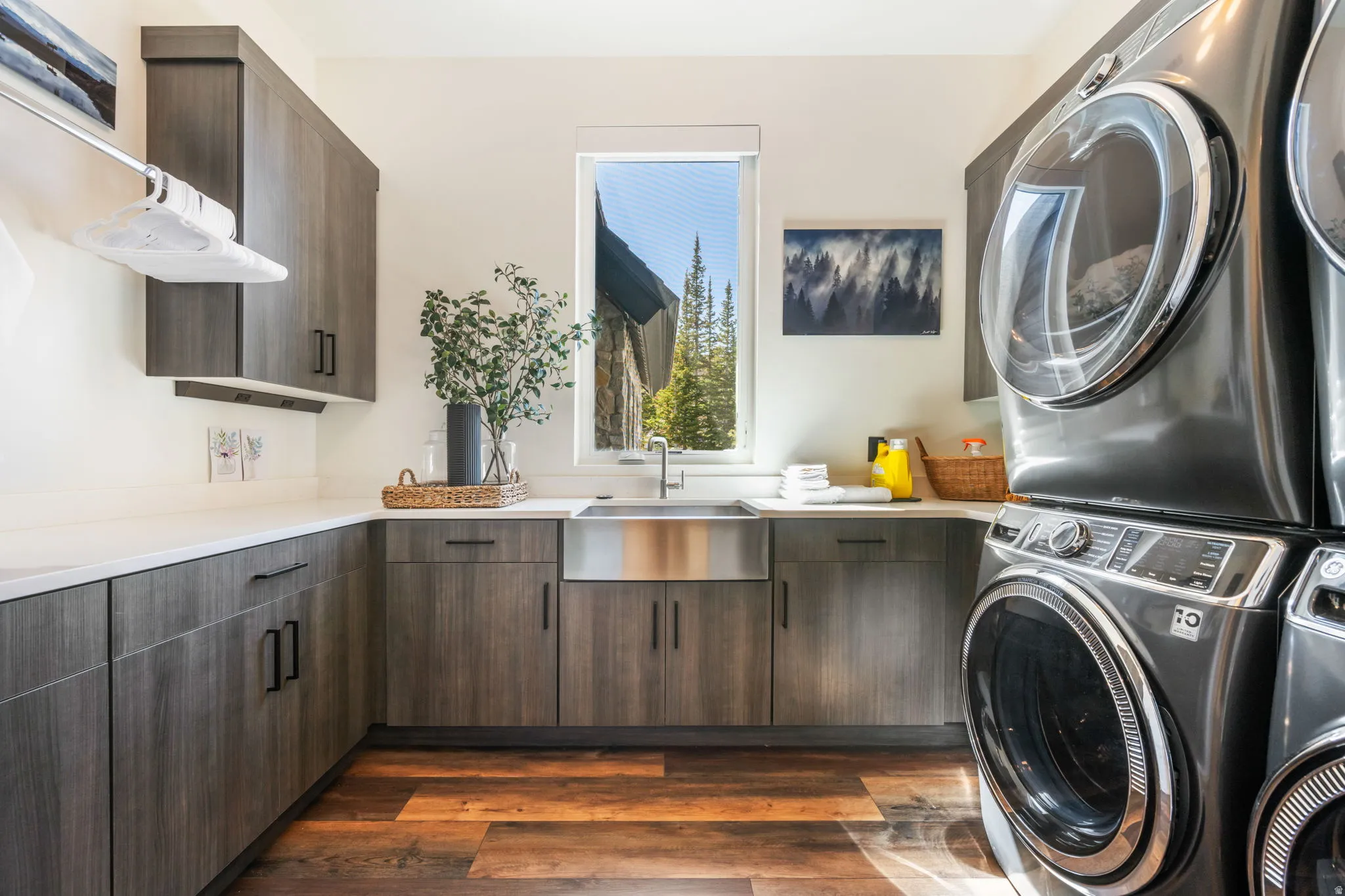 Laundry room with cabinet space, stacked washer and clothes dryer, and dark wood-style floors