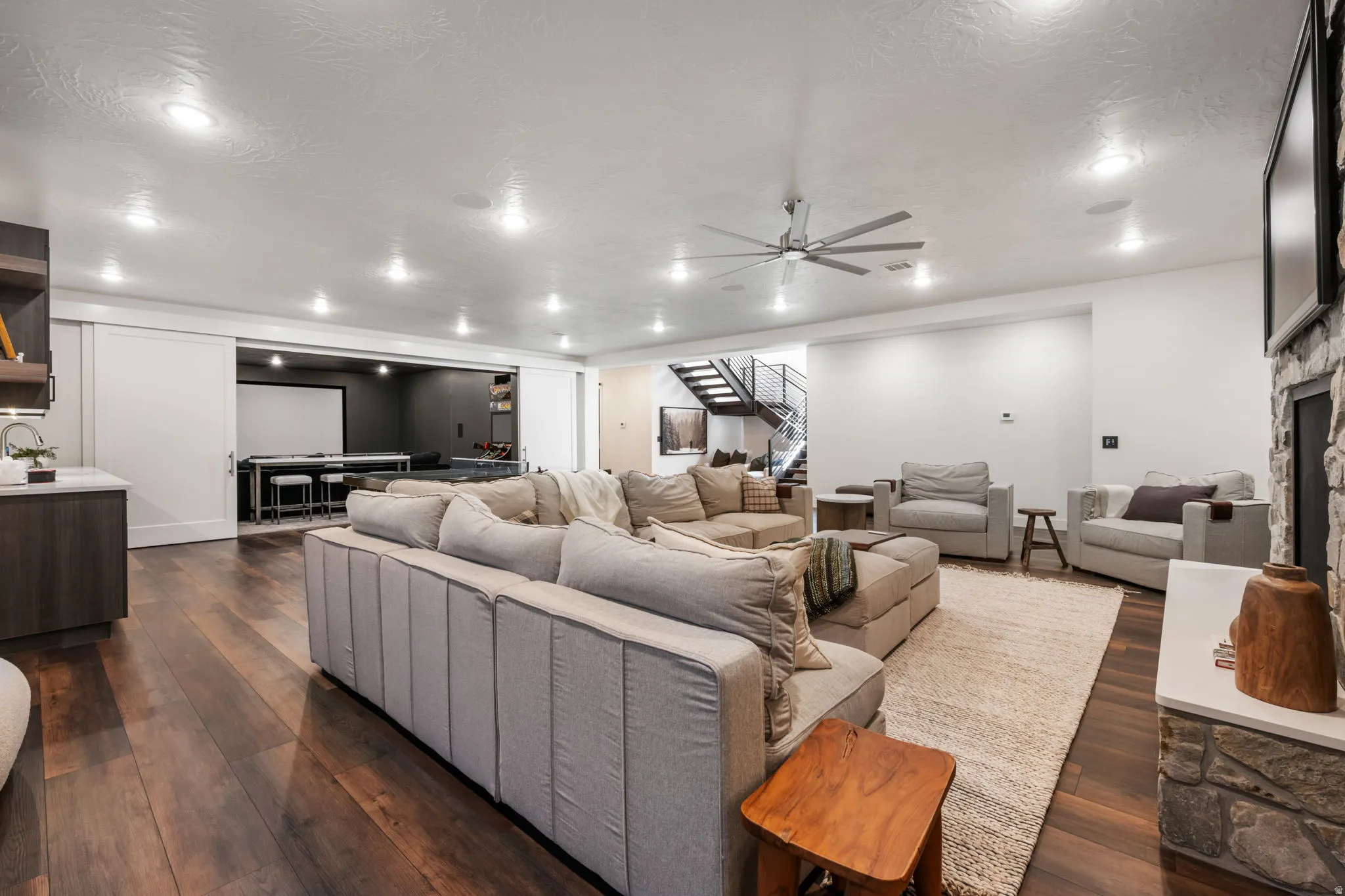 Living room with dark wood finished floors, ceiling fan, a fireplace, a textured ceiling, and recessed lighting