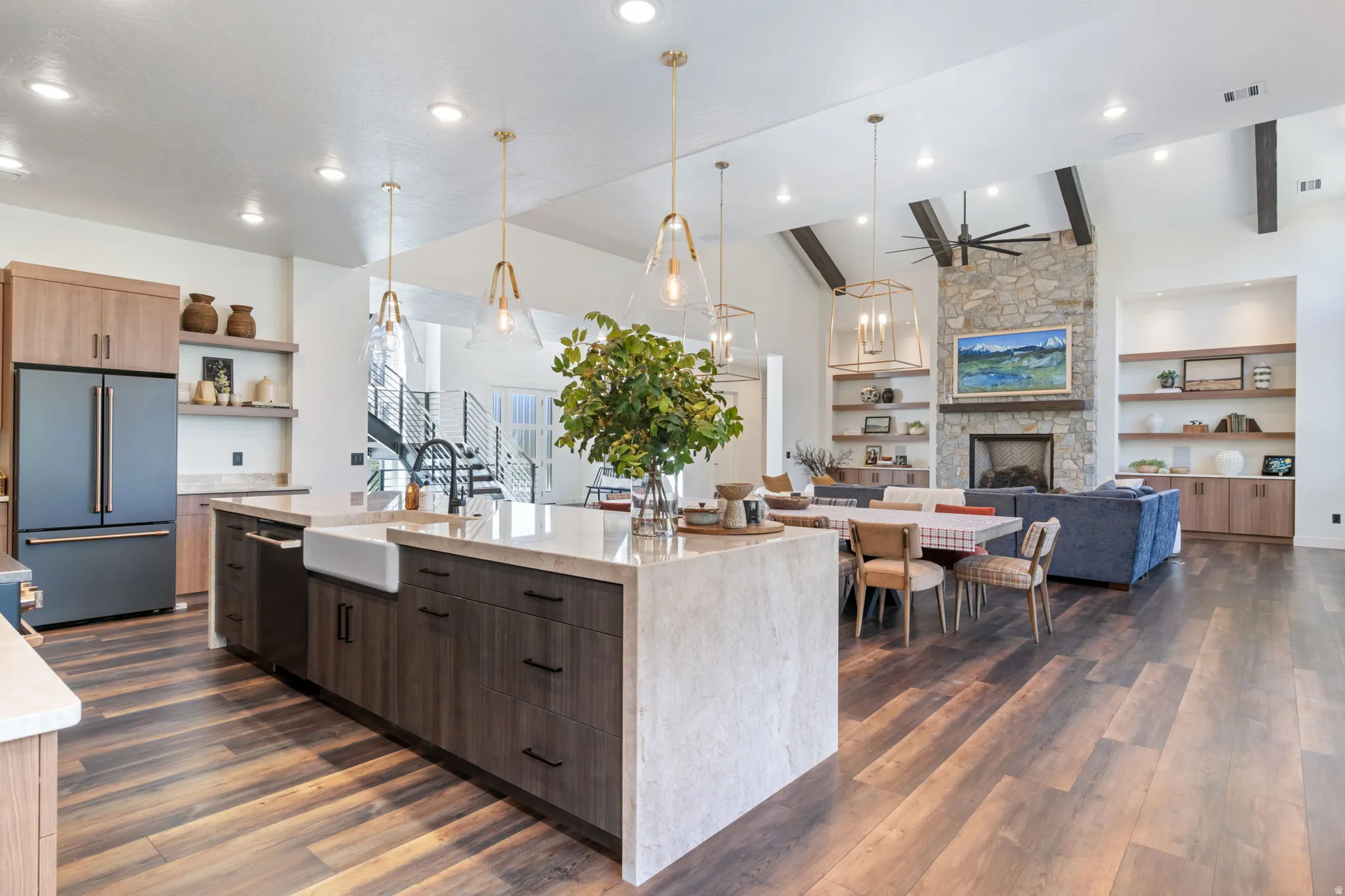Dual tone kitchen featuring high quality fridge, open floor plan, light stone countertops, two tone color scheme, and a spacious island