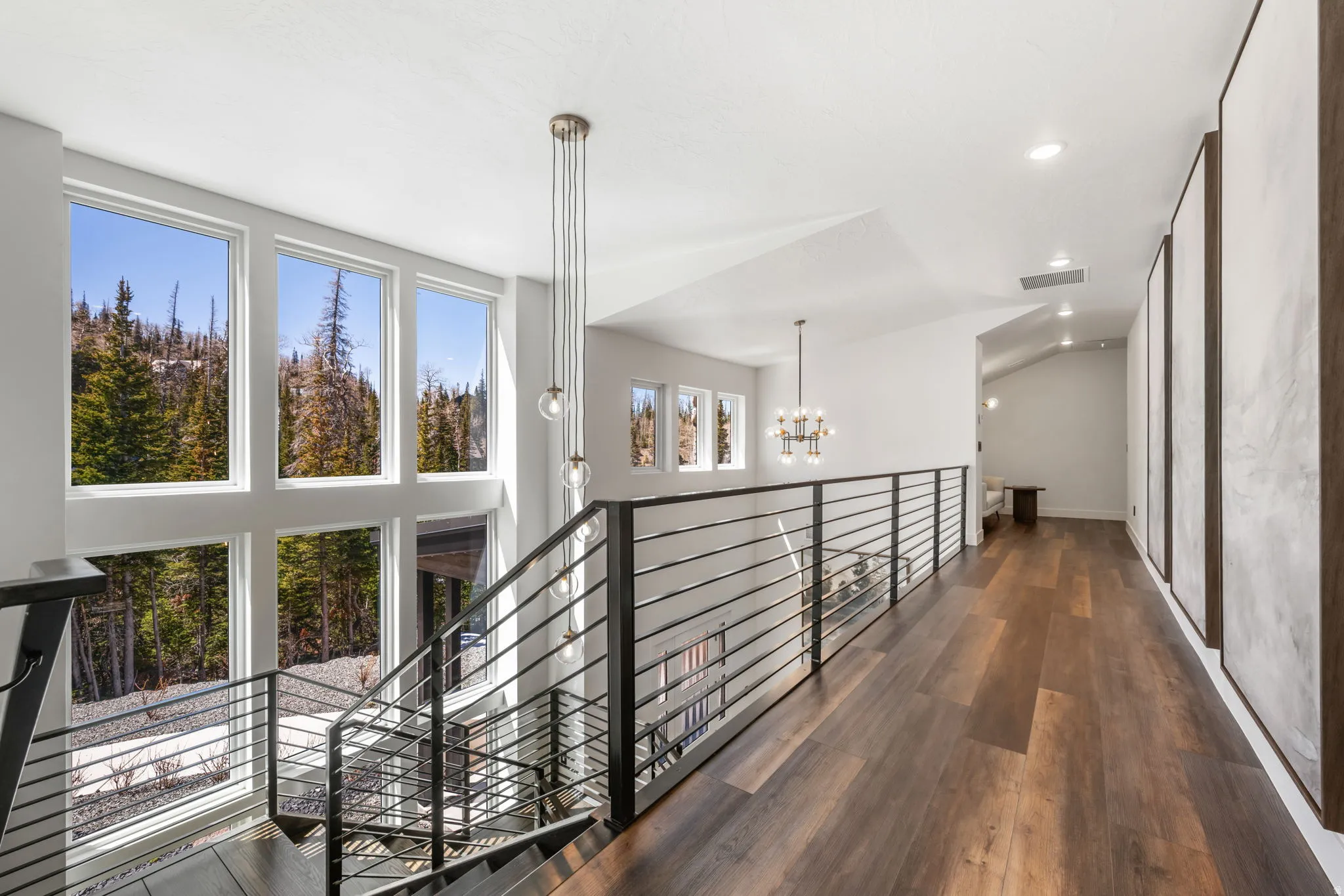 Hall featuring dark wood-type flooring, suspended lighting, an upstairs landing, and lofted ceiling