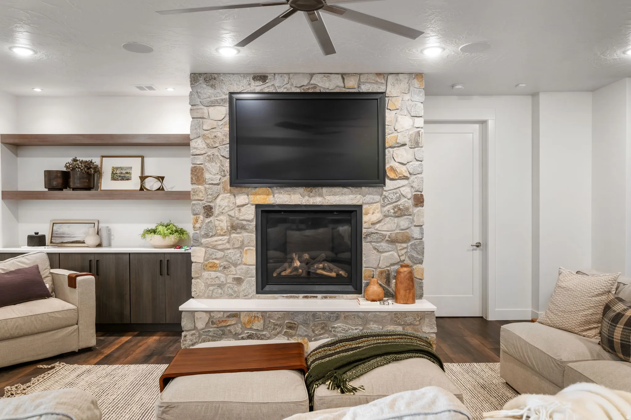 Living area with a ceiling fan, dark wood-style floors, a fireplace, and a textured ceiling
