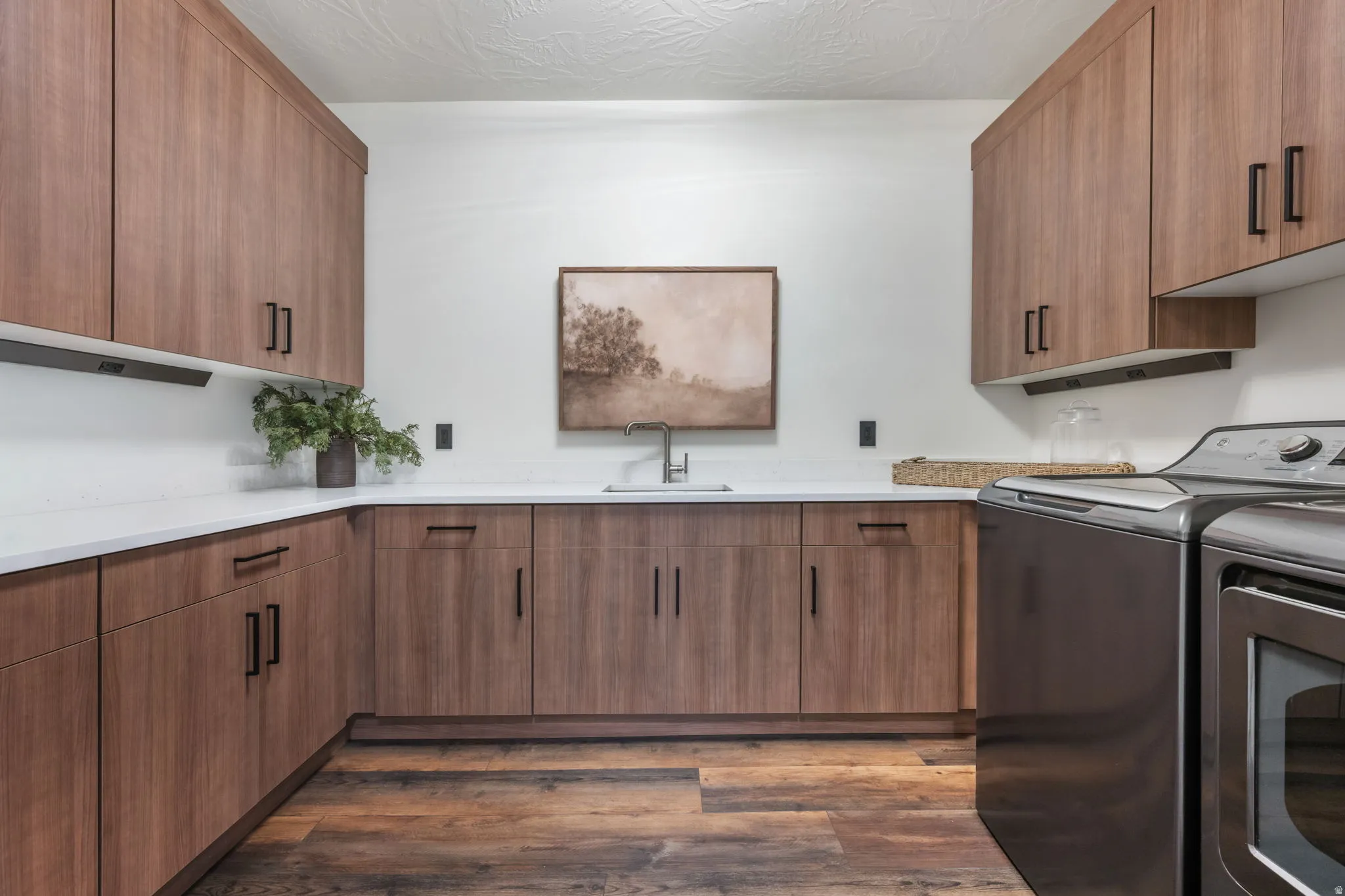 Laundry area featuring cabinet space, washing machine and dryer, and dark wood-style flooring