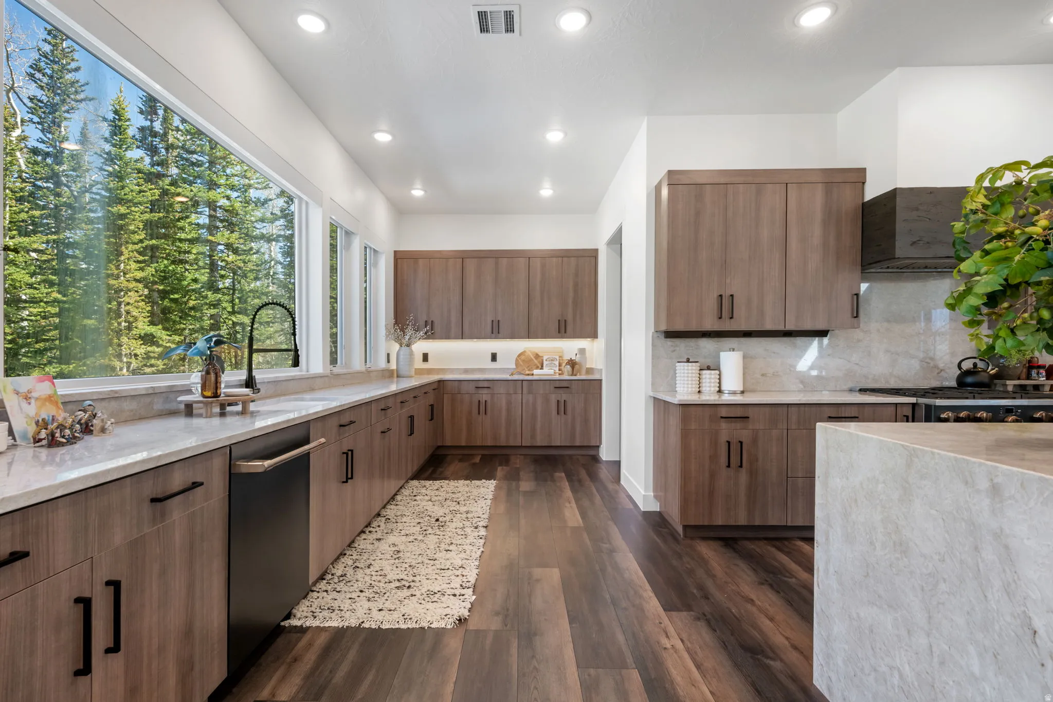 Kitchen with light stone countertops, dark wood-style flooring, modern cabinets, stainless steel dishwasher, and recessed lighting