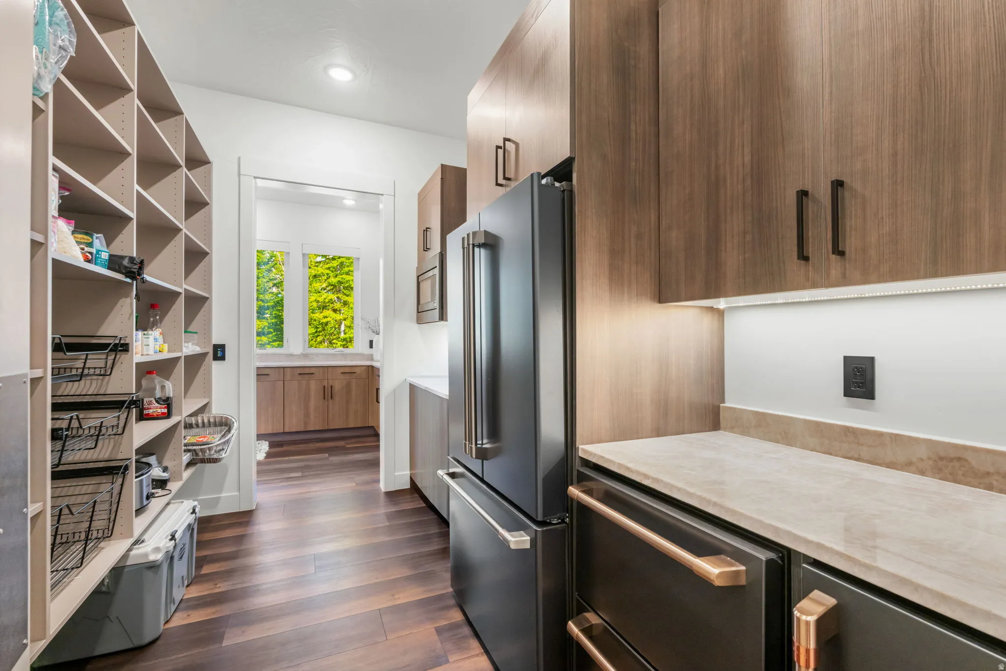Kitchen featuring modern cabinets, light stone countertops, high end fridge, dark wood-style floors, and recessed lighting