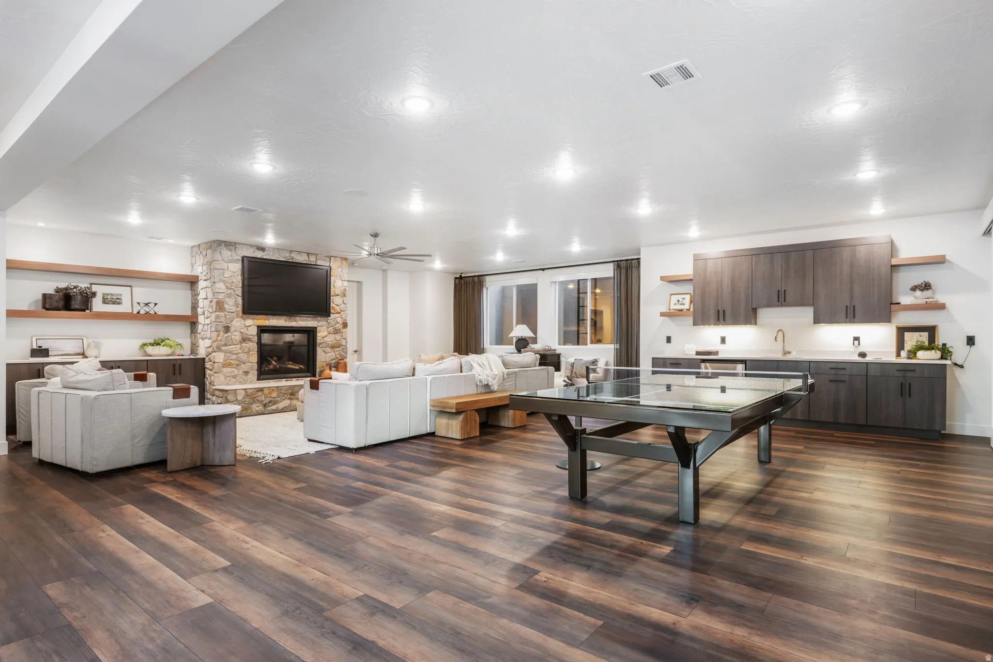 Living room featuring dark wood-style flooring, a ceiling fan, and a fireplace