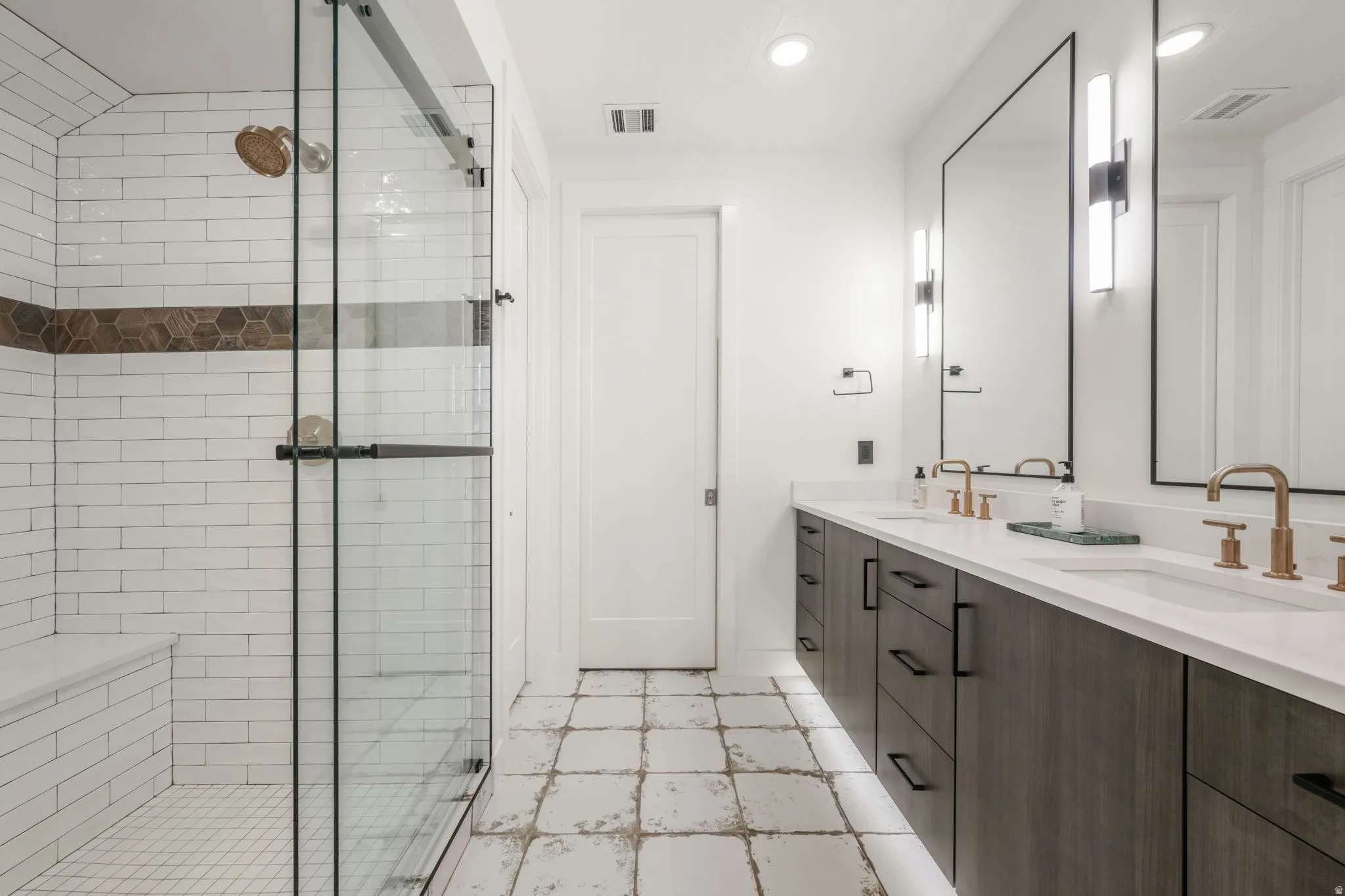 Bathroom with double vanity, a shower stall, and recessed lighting