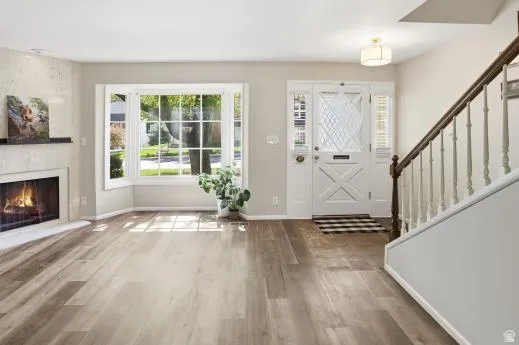 Entrance foyer with wood finished floors and a warm lit fireplace